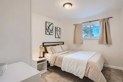 a white bedroom with a bed and a window at Serene, Spacious Home in Quiet Neighborhood with Fenced Yard in Aurora