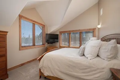 a bedroom with a bed with white sheets and a television at Stagecoach Cabin home in Fraser