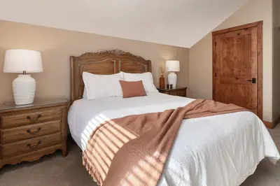 a bedroom with a large bed with a wooden headboard at Stagecoach Cabin home in Fraser