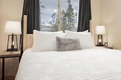 a bedroom with a bed with white pillows and a window at Grand Chalet at Grand Lake cabin in Grand Lake