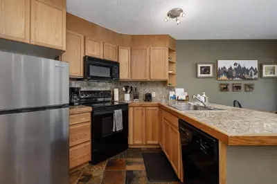 a kitchen with wooden cabinets and a stainless steel refrigerator at Iron Horse C4093 condo in Winter Park