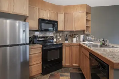 a kitchen with wooden cabinets and a stainless steel refrigerator at Iron Horse C4093 condo in Winter Park
