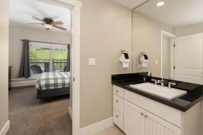 a bathroom with a sink and a mirror and a bed at Base Camp 313 condo in Granby