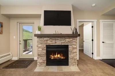 a living room with a fireplace with a tv above it at Base Camp 313 condo in Granby