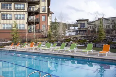 a row of lounge chairs next to a swimming pool at Base Camp 313 condo in Granby