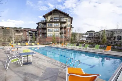 a pool with chairs and a table and a building at Peak View Drive townhouse in Granby