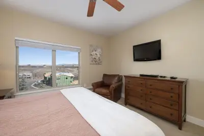 a bedroom with a bed and a television and a chair at Base Camp 306 condo in Granby