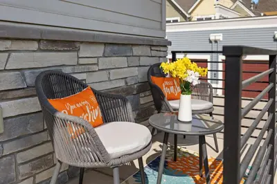 two chairs and a table with flowers on a patio at Upbeat Retreat - Enjoy Bikes, Brews and Mtn Peaks! in Fort Collins