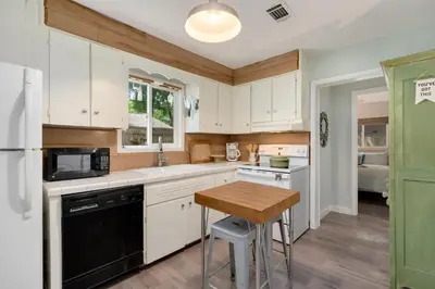 a kitchen with white cabinets and a wooden table at Old Town Retreat w Vintage Flair Near CSU, Bikes! in Fort Collins