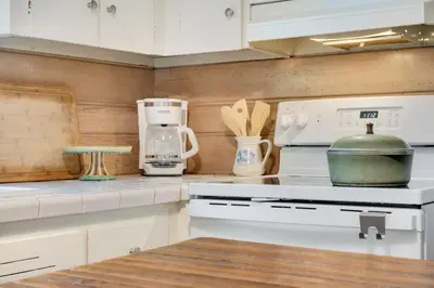 a kitchen with white cabinets and a stove top oven at Old Town Retreat w Vintage Flair Near CSU, Bikes! in Fort Collins