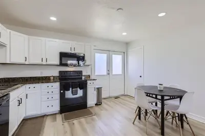 a kitchen with white cabinets and a table with chairs at 15-mins from DIA, Fenced-Yard, Garage, Remodeled in Aurora