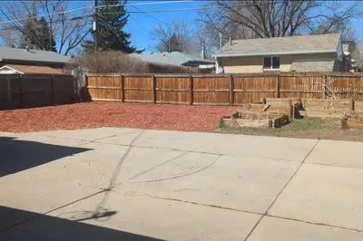 a backyard with a wooden fence and a driveway at 1000 Dollar Rebate if You Buy A Home in Denver in Lakewood