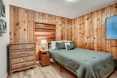 a bedroom with a bed and a wooden wall at 1,000 Per Month Rebate When Buying A Home in Lakewood