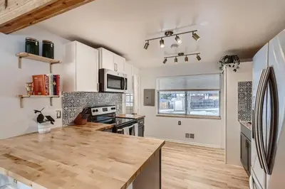 a kitchen with white cabinets and a wooden counter top at 1,000 Dollars For Each Month Stayed When Moving to Colorado in Arvada