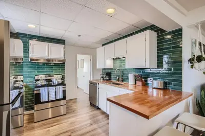 a kitchen with white cabinets and green tiles at 1000 Dollar Rebate if You Buy A Home in Denver in Lakewood