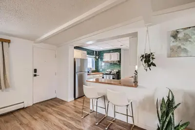 a kitchen with white walls and a table and chairs at 1000 Dollar Rebate if You Buy A Home in Denver in Lakewood