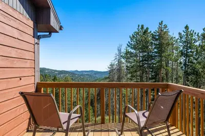 two chairs on a deck with mountains in the background at Mountain View Apartment Near Downtown & Trails in Evergreen