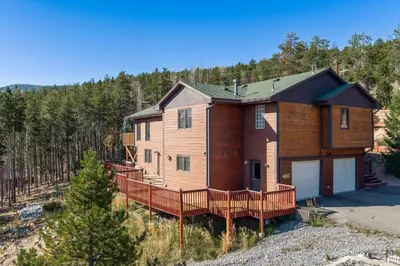 a large house with a large deck in the woods at Mountain View Apartment Near Downtown & Trails in Evergreen