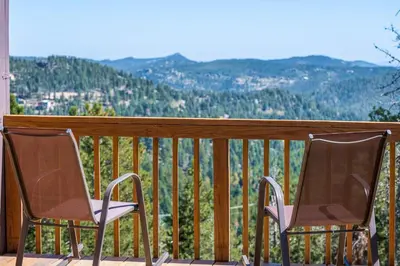 two chairs sitting on a balcony with a view at Mountain View Apartment Near Downtown & Hiking in Evergreen