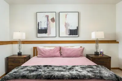 a bedroom with a pink bed with two lamps at Mountain View Apartment Near Downtown & Hiking in Evergreen