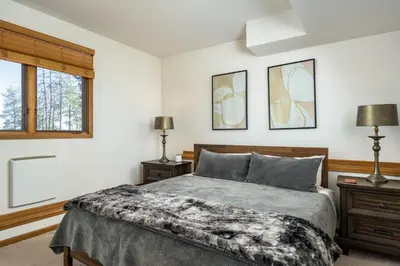 a bedroom with a bed and two lamps and a window at Mountain View Apartment Near Downtown & Hiking in Evergreen