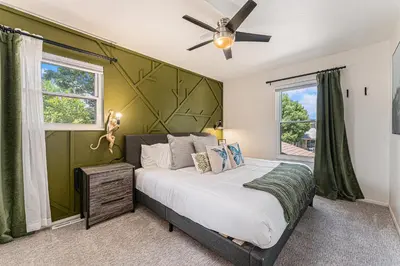 a bedroom with a bed with a green accent wall at All-In-One Retreat Spa, Gym, Fun Room & Location! in Arvada