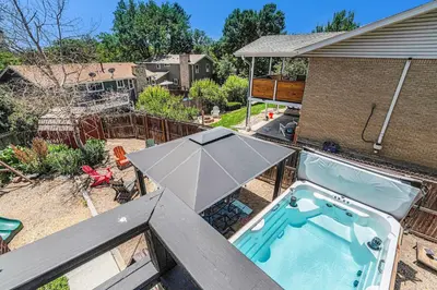 a hot tub with an umbrella on a patio at All-In-One Retreat Spa, Gym, Fun Room & Location! in Arvada