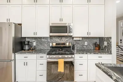a kitchen with white cabinets and a stove at Outdoor Living and comfort by RiNo BBQ Office in Denver
