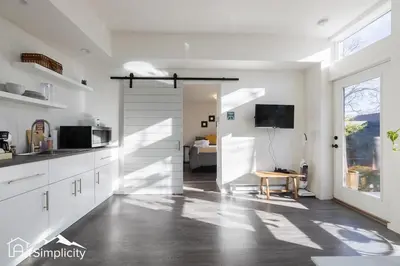 a kitchen with white cabinets and a sliding door at Sunnyside guesthouse near Rocky Mountain Lake in Denver