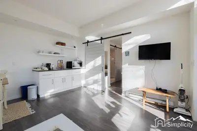 a kitchen with white cabinets and a tv on the wall at Sunnyside guesthouse near Rocky Mountain Lake in Denver