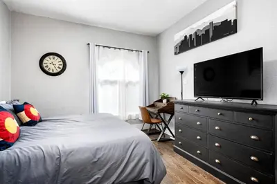 a bedroom with a bed and a dresser with a flat screen tv at Work-Friendly Denver Stay - Rooftop Deck & Garden in Denver