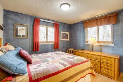 a bedroom with a bed and a dresser and windows at Riverside Condo in Downtown Winter Park! in Winter Park
