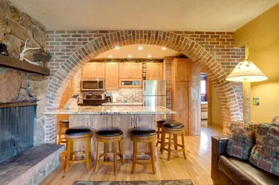 a kitchen with a stone archway and bar stools at Riverside Condo in Downtown Winter Park! in Winter Park