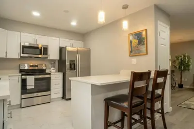 a kitchen with white cabinets and a counter with chairs at Close to Downtown Sleeps 8 Private Backyard in Arvada