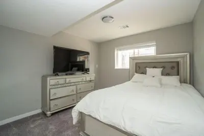 a bedroom with a white bed and a television at Close to Downtown Sleeps 8 Private Backyard in Arvada