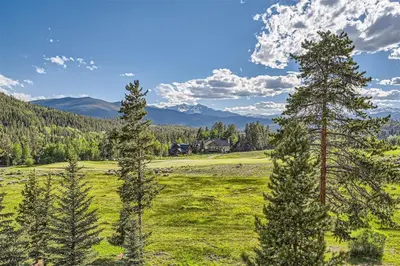 a field with trees and a house in the distance at 2151 The Pines condo in Keystone