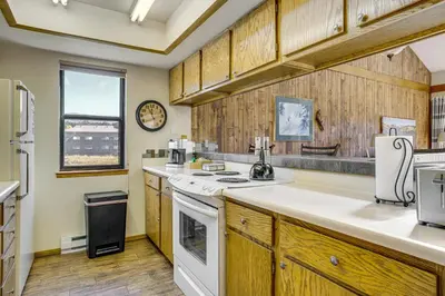 a kitchen with wooden cabinets and a white stove top oven at 6 Mi to Winter Park Resort Fraser Condo with Pool in Fraser