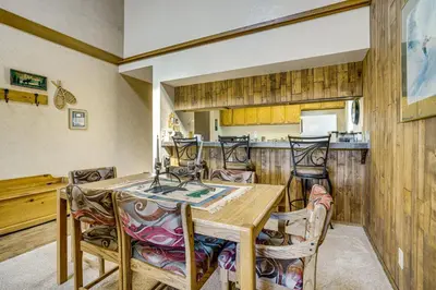 a kitchen and dining room with a wooden table and chairs at 6 Mi to Winter Park Resort Fraser Condo with Pool in Fraser