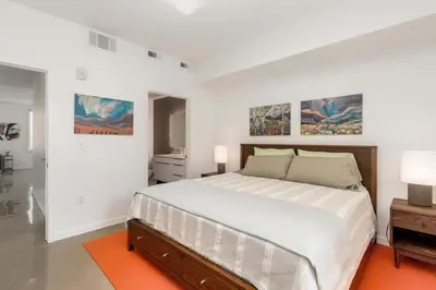 a white bedroom with a large bed and paintings on the walls at Modern Elegance on Linden - Walk, Bike Everywhere! in Fort Collins