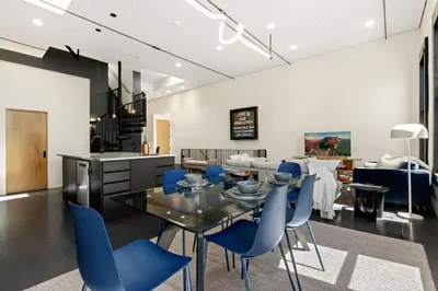 a dining room with a glass table and blue chairs at NEW! Modern Scandinavian Loft in Old Town Square in Fort Collins