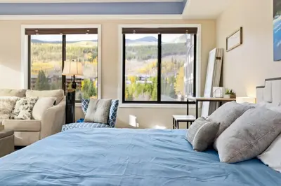 a bedroom with a blue bed and a couch and windows at 2782 Slopeside condo in Keystone