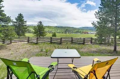 a table and chairs on a wooden deck with a view of a field at Central Fraser Vacation Rental with Private Hot Tub! in Fraser
