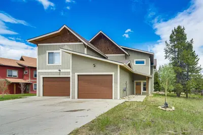 a house with two garage doors in a yard at Central Fraser Vacation Rental with Private Hot Tub! in Fraser