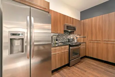 a stainless steel refrigerator in a kitchen with wooden cabinets at The Cozy Corner Retreat, 15 min walk to Old Town in Fort Collins
