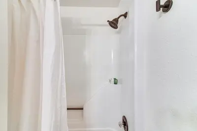 a shower with a white shower curtain in a bathroom at Hike, Bike, Ski Winter Park Condo with Deck in Winter Park