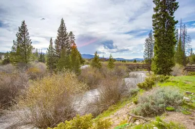 a rainbow in the sky over a river with trees at Hike, Bike, Ski Winter Park Condo with Deck in Winter Park