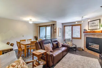 a living room with a leather couch and a dining room at Cozy Ski-InandSki-Out Winter Park Condo with Pool! in Winter Park