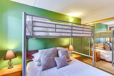 a bedroom with two bunk beds and a green wall at Cozy Ski-InandSki-Out Winter Park Condo with Pool! in Winter Park