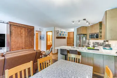 a kitchen with wooden cabinets and a dining room at Cozy Ski-InandSki-Out Winter Park Condo with Pool! in Winter Park
