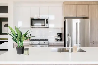 a white kitchen with a stainless steel refrigerator at Serenity in Style | Espadin LoHi in Denver